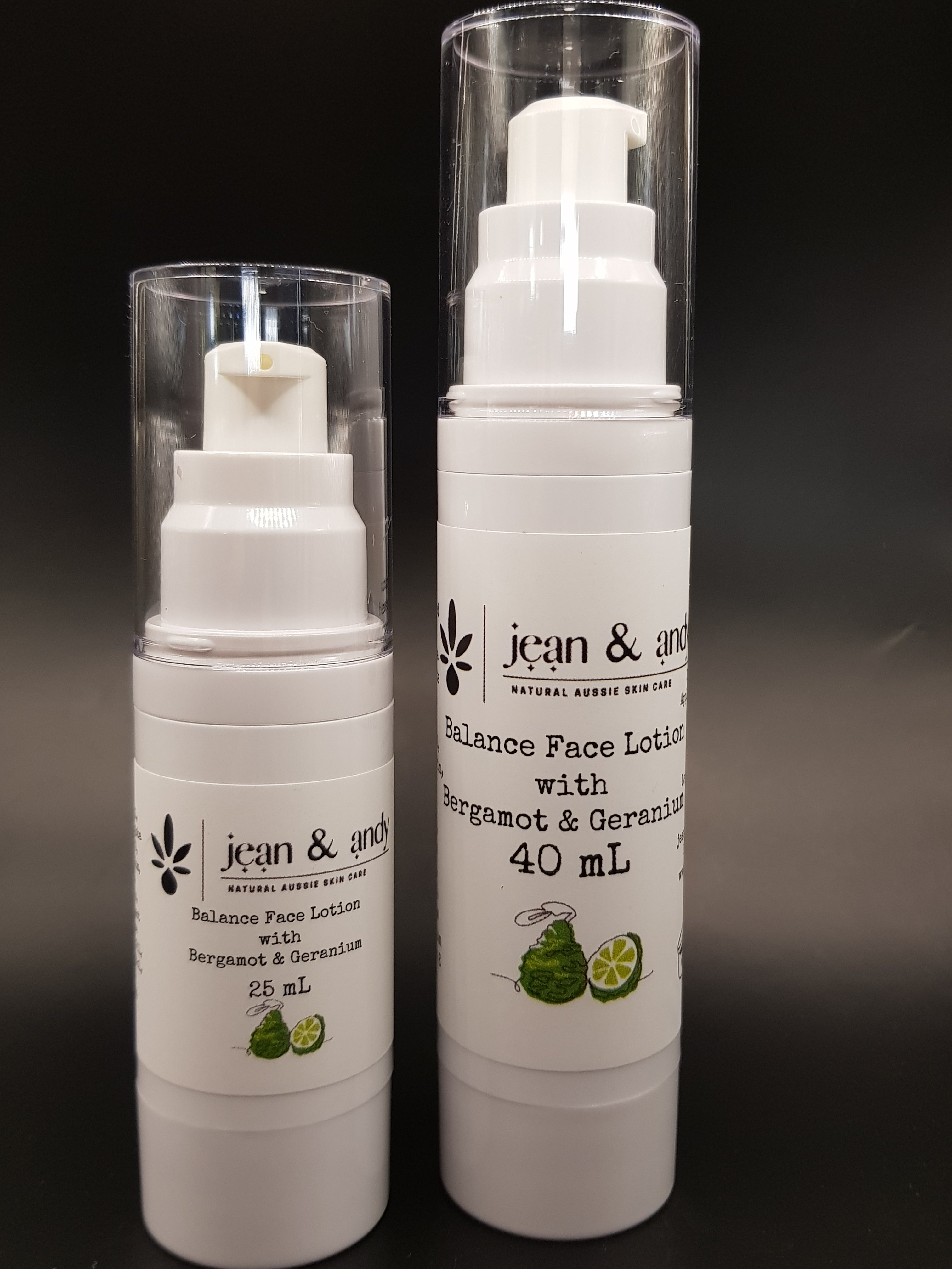 Against a black background, two white bottles of the Bergamot Balancing Face Lotion by jean & andy are displayed. The bottles, available in 25 ml and 40 ml sizes, are enriched with bergamot and geranium essential oils along with nourishing jojoba oil.