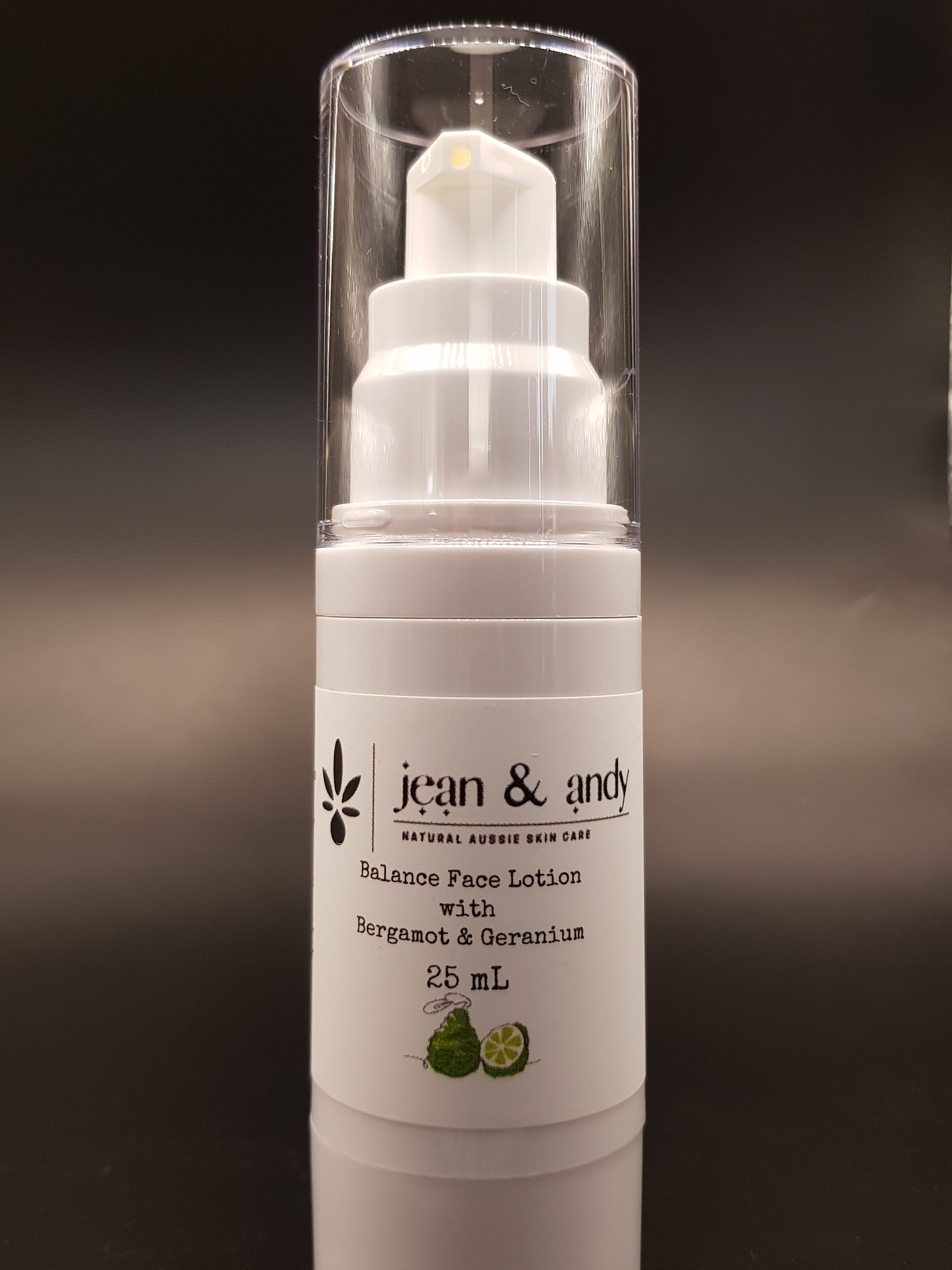 Clear bottle of Bergamot Balancing Face Lotion featuring a white pump dispenser, labeled with jean & andy Bergamot Balancing Face Lotion and Geranium, 25 mL. Infused with Grapeseed Oil, the design boasts a simple black label adorned with a plant graphic.