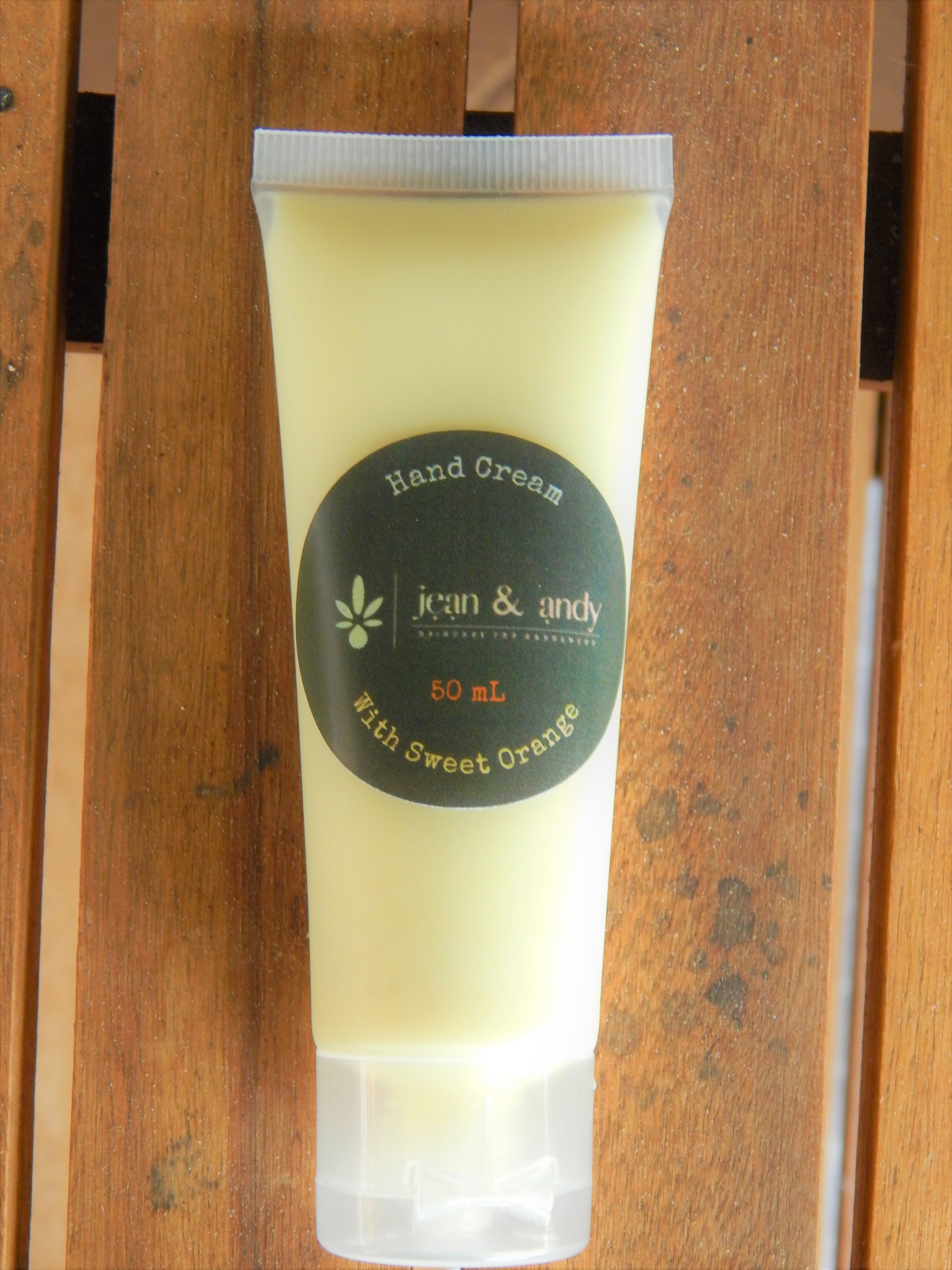 "A tube of Sweet Orange Hand Cream, enriched with unrefined avocado oil, shea and mango butters, carrot tissue oil, aloe vera, and botanical extracts, offering soothing hydration and a refreshing citrus scent."